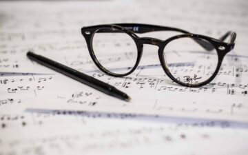 sheet music with glasses and pen.
